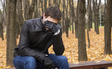 A man sits on a bench in autumn park