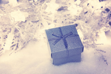Christmas present box in snow with star lights in the background