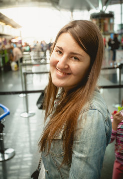 portrait of smiling brunette woman standing at queue in airport