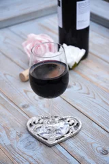 Tapeten glas rode wijn op houten tafel met hart decoratie en roosjes © trinetuzun