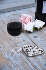 glas rode wijn op houten tafel met hart decoratie en roosjes