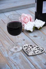 Fototapeten glas rode wijn op houten tafel met hart decoratie en roosjes © trinetuzun