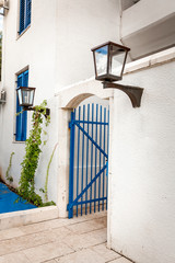 blue gates in white wall with gas lamp at greek style