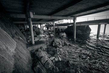 Monochrome  photo of beach under the old wooden pier - Powered by Adobe