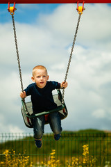 Little boy having fun at the playground on swing