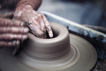 Hands working on pottery wheel ,  artistic  toned