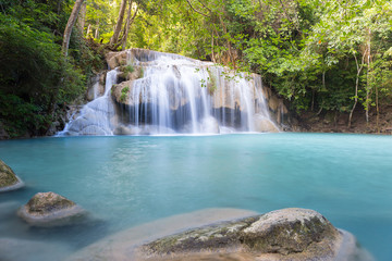 Waterfall, green forest in Erawan National Park, Thailand. Landscape with water flow, river, stream and rock at outdoor. Beautiful scenery of nature for tourist to tour, visit, relax in vacation.