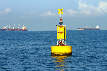 Floating yellow navigational buoy on blue sea
