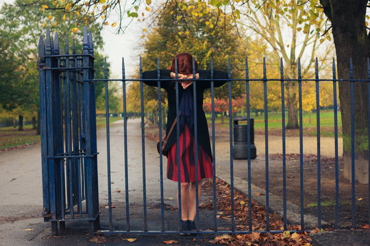 Sad woman leaning on gate in park