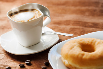 Appetizing cup of coffee with doughnut.