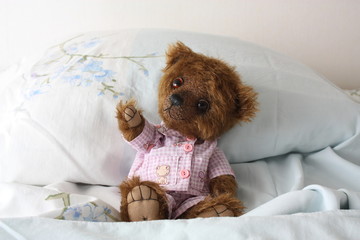 Teddy bear resting on the bed in pajama
