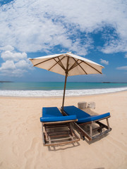 Relaxing couch chairs with parasol on white sandy Beach