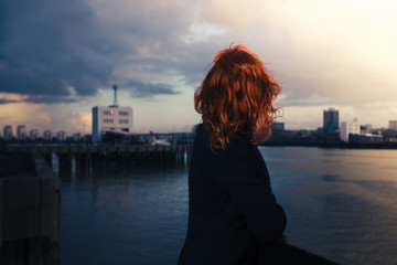 Fototapeta na wymiar Woman admiring sunset over river in city