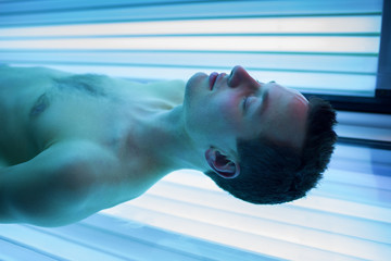 Handsome young man relaxing during a tanning session i