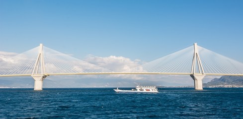Naklejka premium Ferry boat sailing under suspension bridge