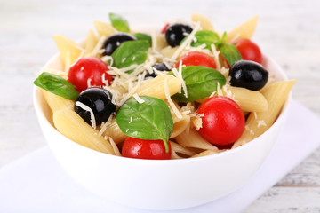 Pasta with tomatoes, olives and basil leaves in bowl