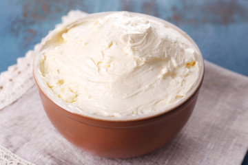 Fresh homemade butter in bowl, on color wooden background