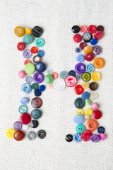 Letter H of the alphabet of buttons of various shapes and colors