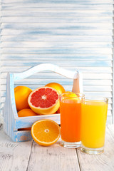 Orange and carrot juice in glasses and fresh fruits in wooden