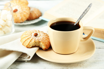 Cup of coffee with tasty cookie on color wooden background
