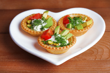 Tartlets with greens and vegetables with sauce on plate on