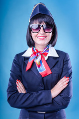 Charming stewardess dressed in bkue uniform. Sunglasses.