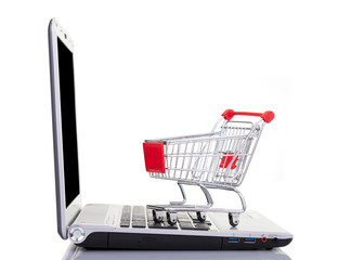 Shopping cart over a laptop computer, isolated on white backgrou