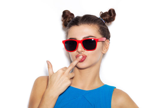Young woman in sunglasses kisssing middle finger