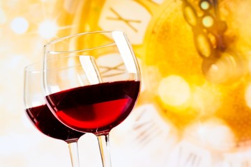 two red wine glasses against golden clock background
