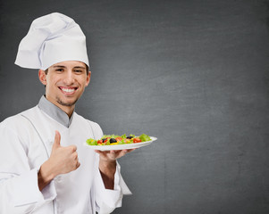 Chef cook with vegetable salad dish thumbs up, grey background