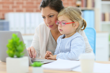 Mother working at home-office with daughter on her lap