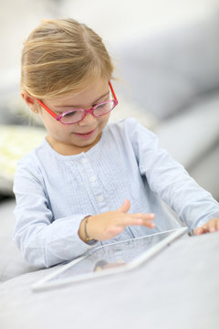 Cute little girl playing with digital tablet