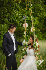 Beautiful bride with fiance is swinging on a swing