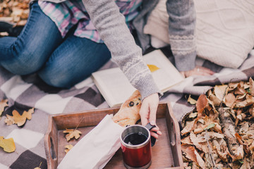 Young woman reading book and drinking tea in a forest