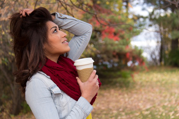Stylish young woman with coffee outdoors during autumn