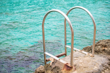 Handrails mounted on rock near the sea.