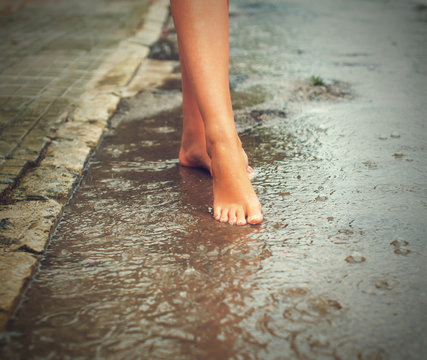 Woman enjoying tropical rain. Legs.