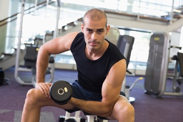 Portrait of man exercising with dumbbell in gym