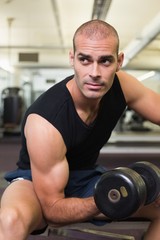 Fototapeta na wymiar Young man exercising with dumbbell in gym