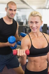 Couple exercising with dumbbells in gym