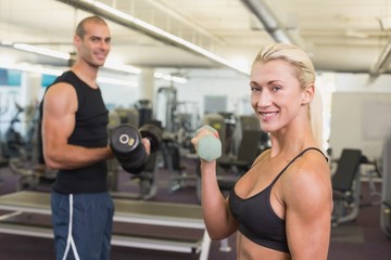 Fototapeta na wymiar Couple exercising with dumbbells in gym