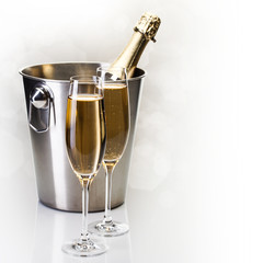 Champagne bottle in bucket with glasses of champagne