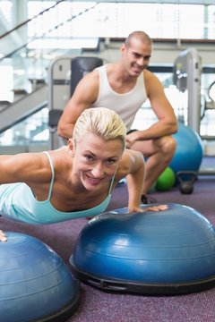 Trainer assisting woman with push ups at gym