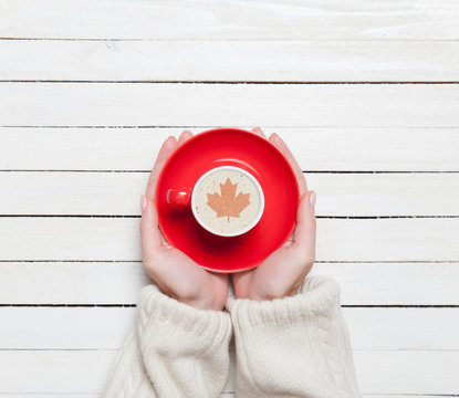 Female hands holding cup of coffee on wooden table.