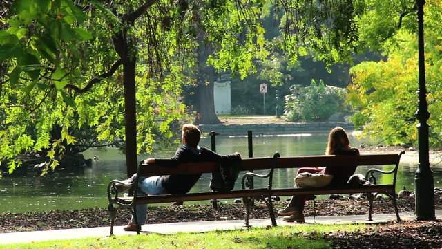 Romantic dating man and woman separately in park benches meeting
