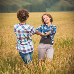 Happy teen boy and girl walking in a rye field