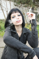 Girl smoke near rails and abandon railroad station