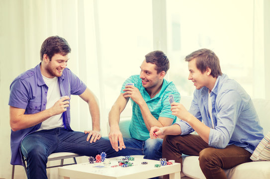 happy three male friends playing poker at home