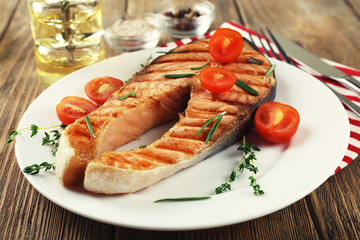 Grilled salmon and vegetables on plate on wooden background