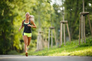 Young lady running. Woman runner running through the park